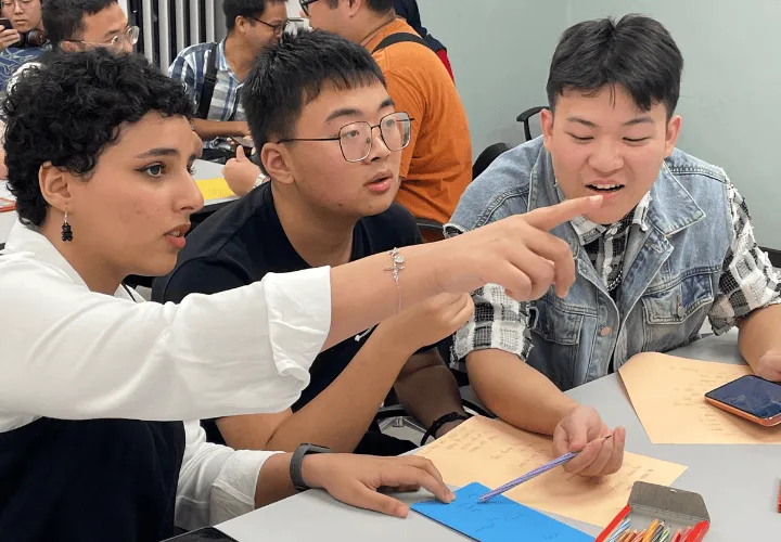Three ELS students in a discussion during a student activity